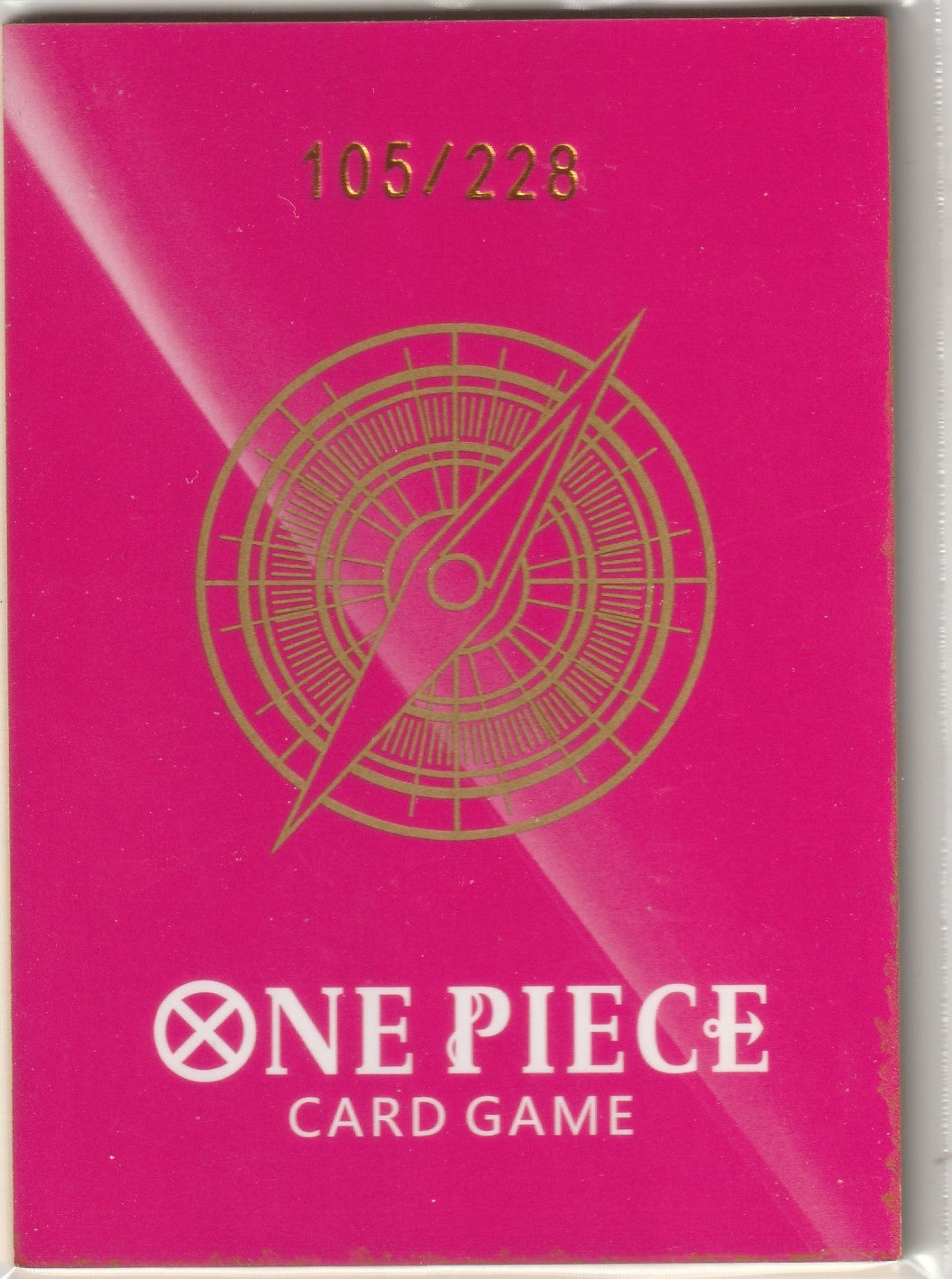 Back of One Piece collectible card with a magenta background, gold compass design, and limited edition number 105/228.