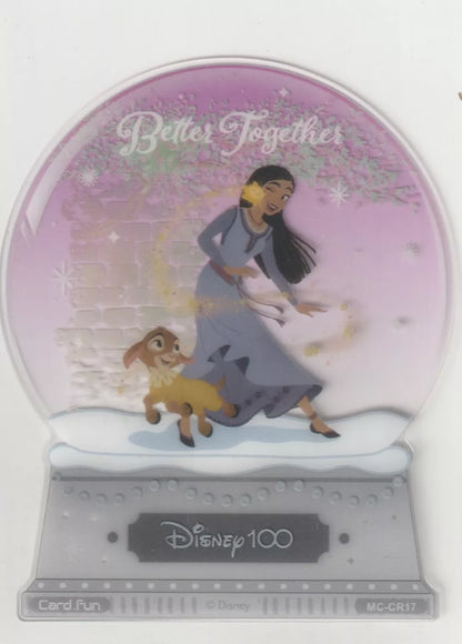 A die-cut snow globe card featuring Asha from Wish and her companion Valentino in a snowy scene, with the text "Better Together."