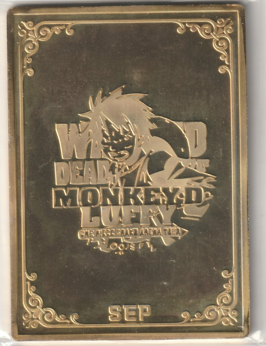 "Metallic gold card with Monkey D. Luffy's embossed 'Wanted' poster design and decorative borders."