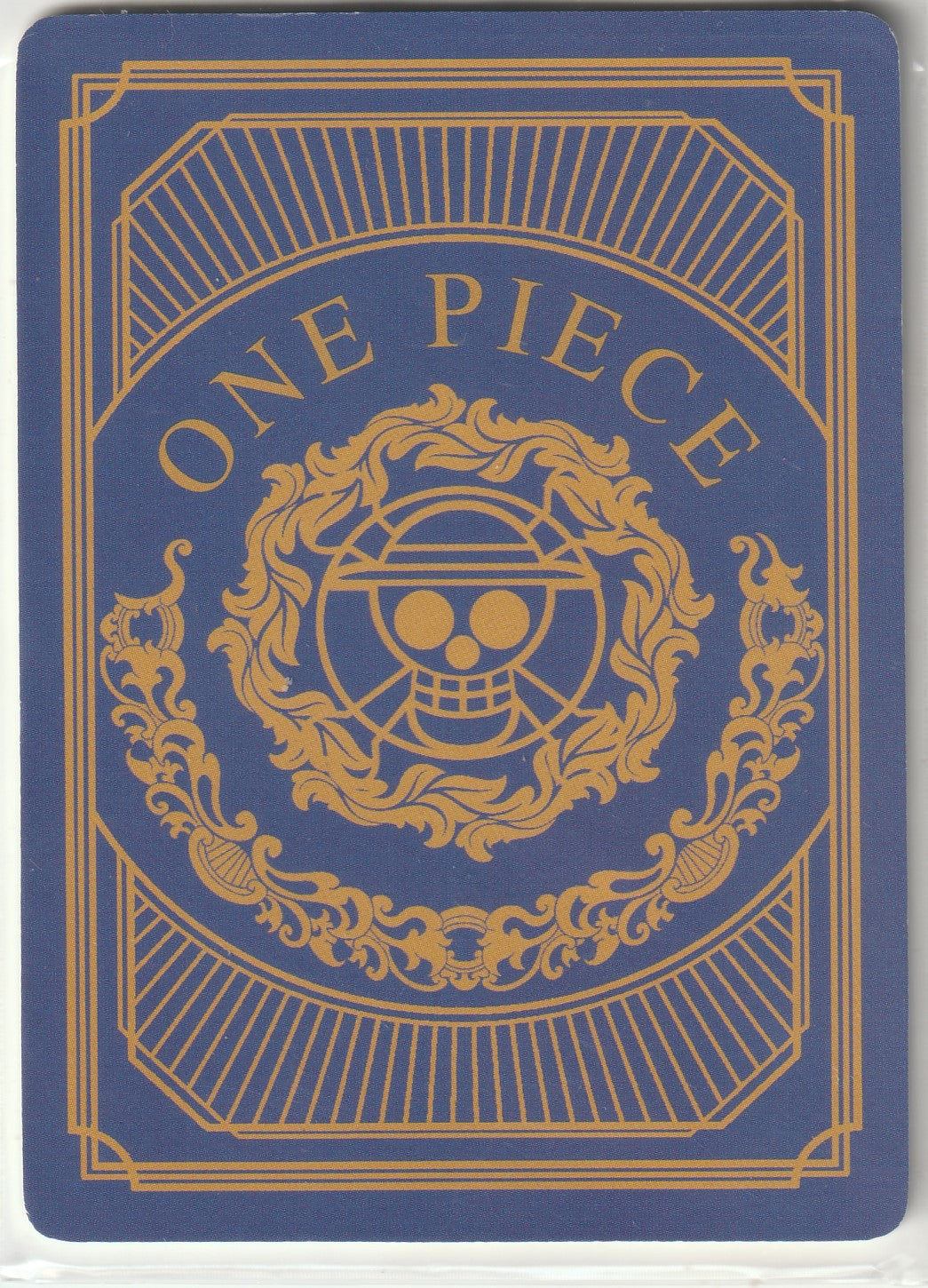 Back of One Piece card displaying the Straw Hat Pirates' Jolly Roger in gold, with 'ONE PIECE' text on a royal blue and gold ornate background.