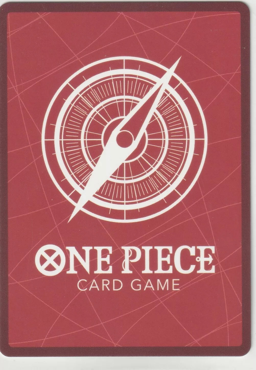 The back of a One Piece TCG card featuring a red background, a white compass, and the One Piece Card Game logo.