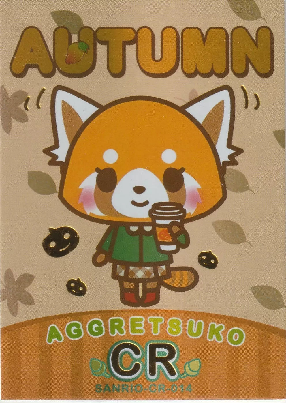 Aggretsuko from Sanrio holding a warm drink, dressed in a green jacket with autumn leaves and pumpkins, accented by foil highlights.